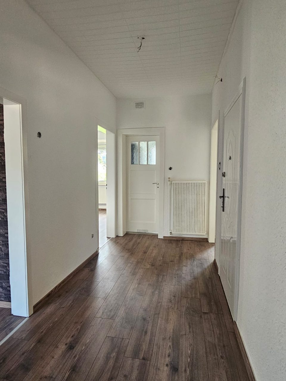 Renovierter Flur mit hellem Anstrich, weißen Türen und neuem Boden